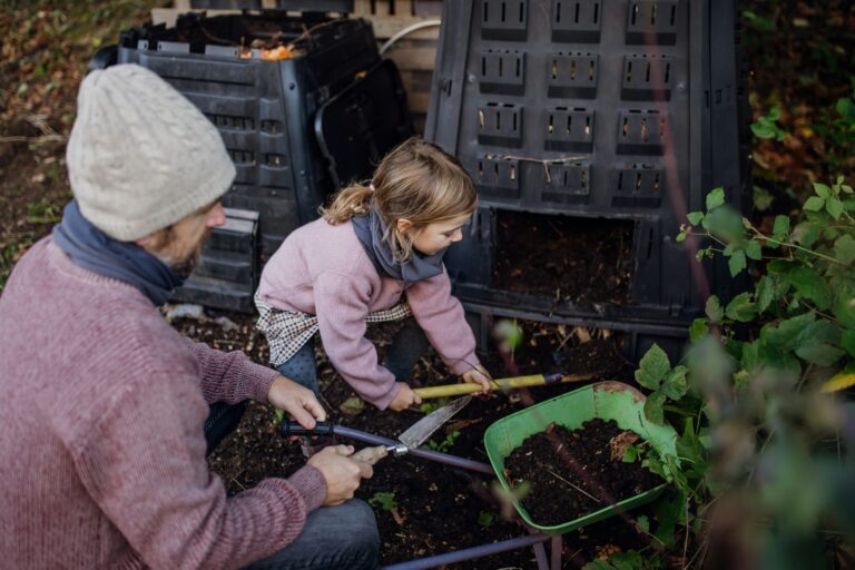 Girl helping father to remove compost from a composter in garden. Concept of composting and