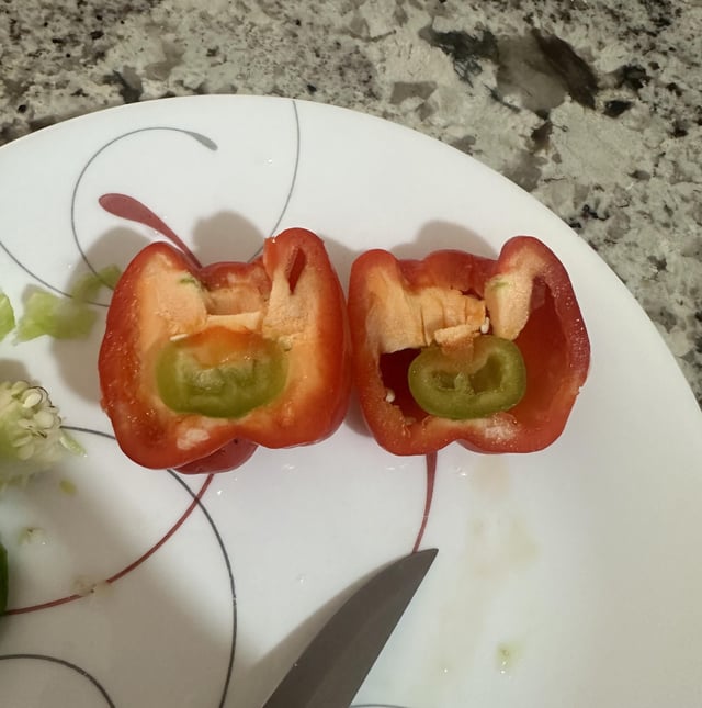 Cut this pepper in half and it looks like it has a little green pepper growing inside of the red pepper. Never seen that before. – Reddit Post
